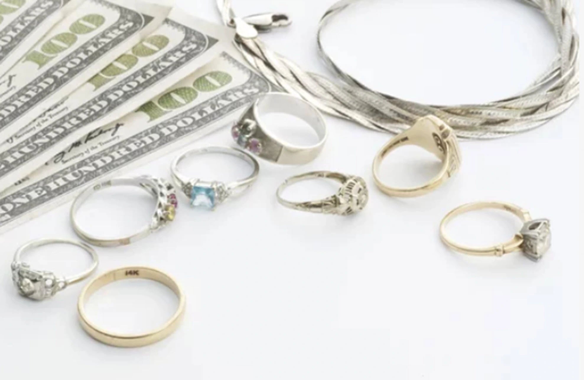Collection of rings and a stack of money on a white surface