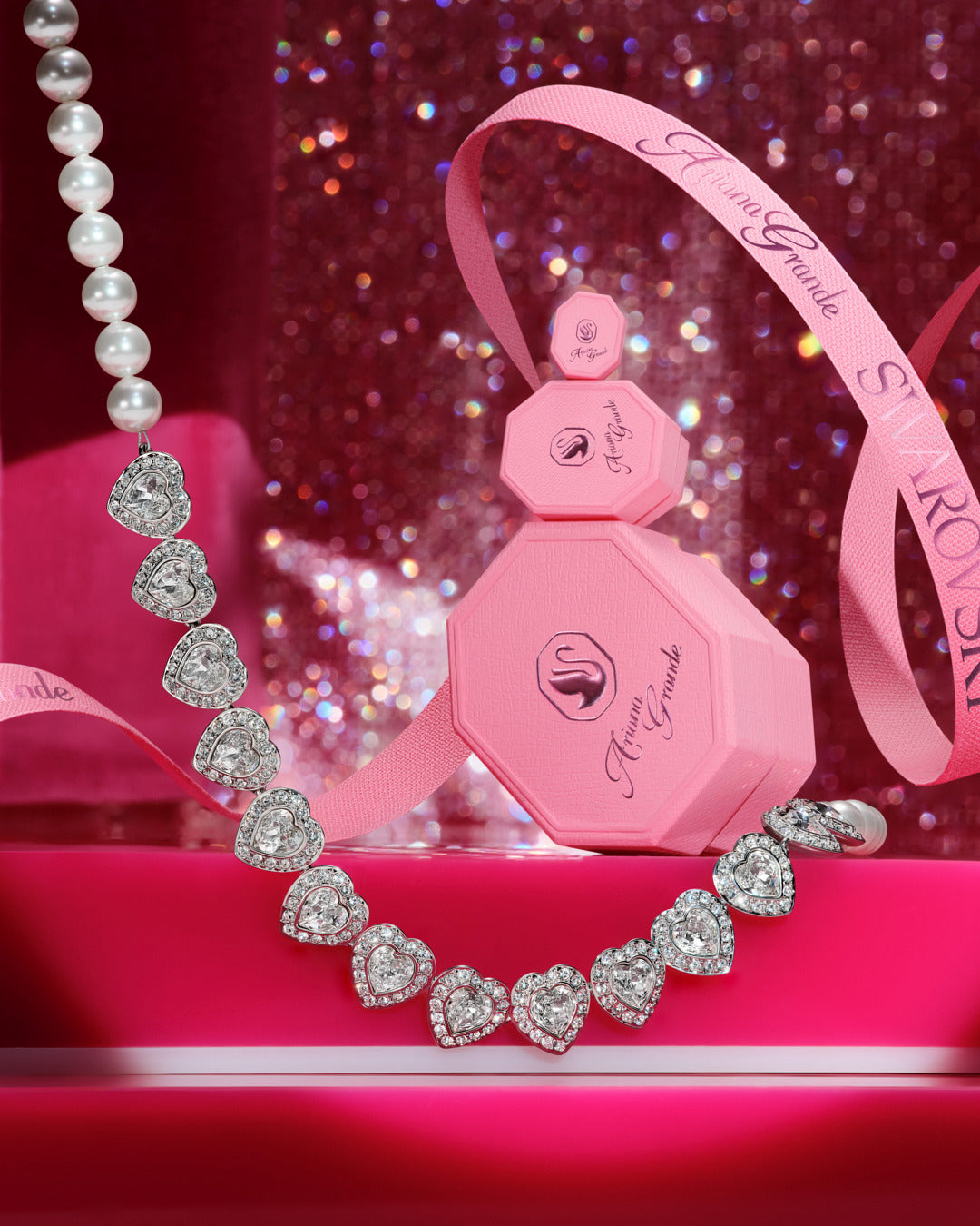 Pink jewelry boxes with heart-shaped jewelry on a glittery pink background