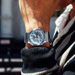 Close-up of a person wearing a silver  Casio G-shock GM2110D-2A wristwatch with a blurred background