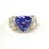 An 18KT yellow gold ring with a 3.07CT trillion tanzanite and diamond inlay, featuring a gold band and a prominent blue tanzanite stone.